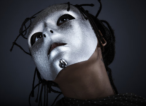 gloomy woman in silver mask posing on a black background.