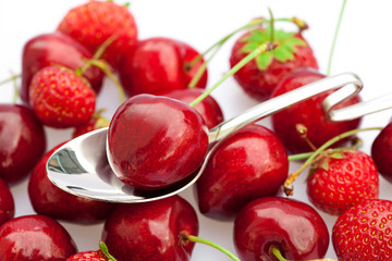 cherry and strawberry in a spoon isolated on white