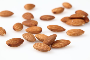Almonds are scattered on a light surface.