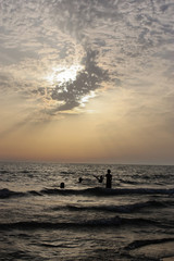 Fototapeta na wymiar bambini che giocano in mare al tramonto