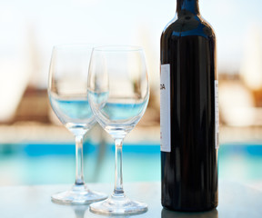 Wine bottle and glasses near sea water