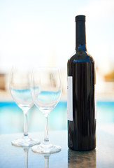 Red wine and glasses near blue water