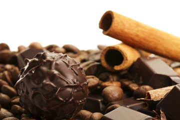 trüffel vor kaffeebohnen und zimtstangen auf schokoladentafel