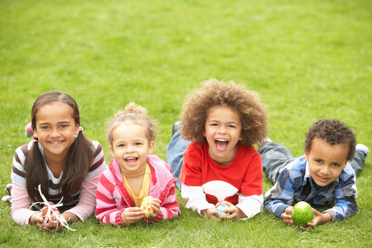 Group Of Children Laying On Grass With Easter Eggs