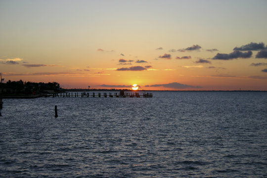 Golden glow of sunset on an ocean bay behind pier