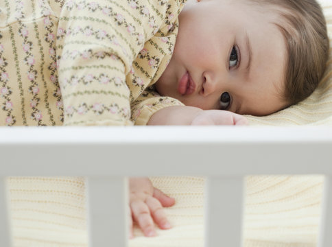 Mixed race baby girl laying in crib