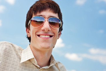 happy man in sunglasses against blue sky