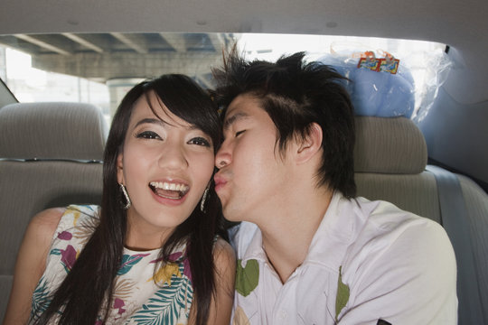 Chinese man kissing girlfriend in back of car