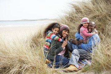 Naklejka na ściany i meble Family Sitting In Dunes Enjoying Picnic On Winter Beach