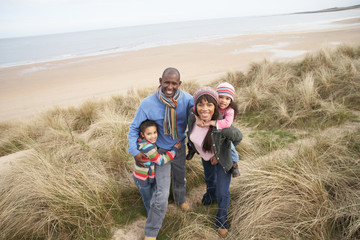 Family Walking Along Dunes On Winter Beach