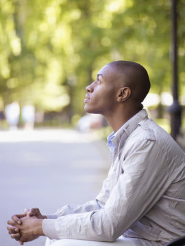 African man looking up with hands clasped
