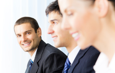 Three successful businesspeople at office, focus on man