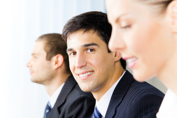 Three successful businesspeople at office, focus on man