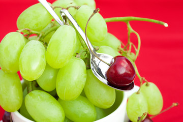 cup of grapes and cherries  on a red background