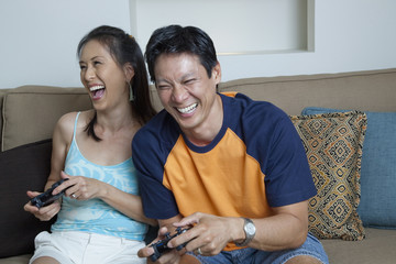 Japanese couple playing video games in living room