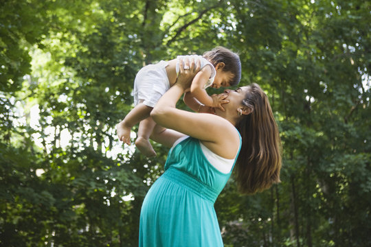 Pregnant Hispanic woman lifting baby boy