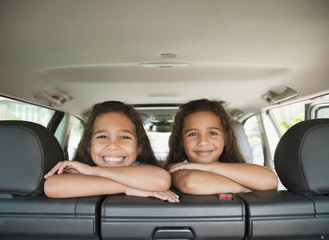 Hispanic sisters in back seat of car
