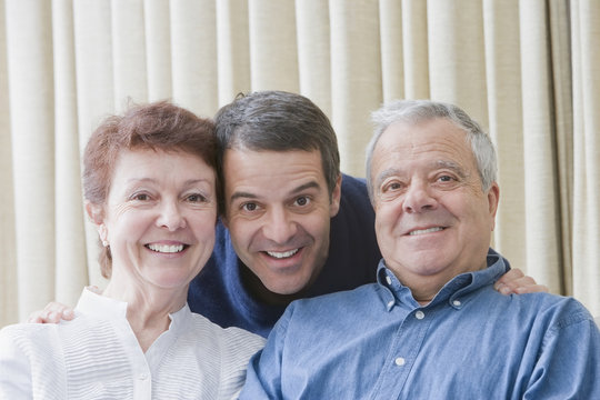 Hispanic parents and adult son smiling