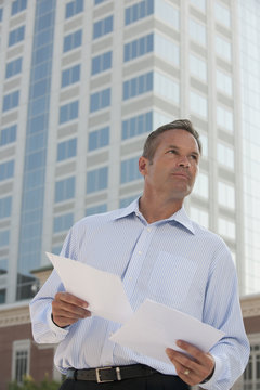 Caucasian businessman holding papers outdoors