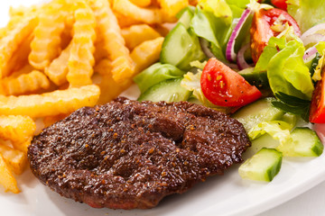 Grilled meat, French fries and vegetables