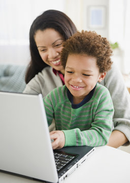 Mixed race mother using laptop with son