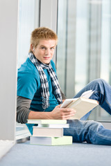 Young man with earbuds and books
