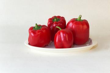 plate of four red peppers against a white background