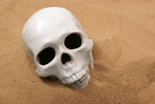 Ceramic human skull in sand