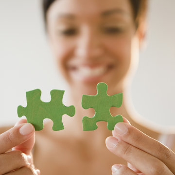Mixed race woman holding green jigsaw puzzle pieces