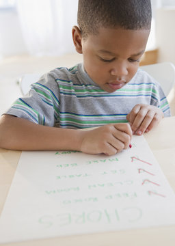 African American Boy Checking List Of Chores