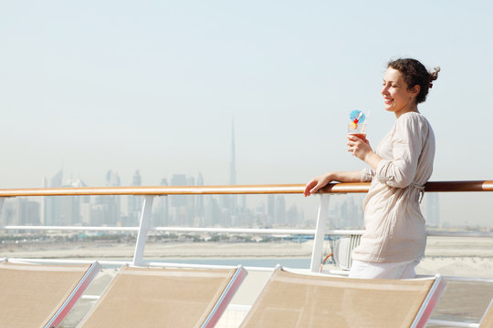 woman with cocktail standing on cruise liner deck