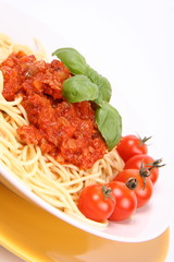 Spaghetti Bolognese on a plate with basil and cherry tomatoes