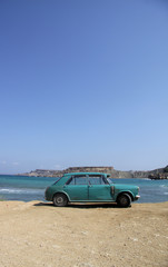 An old rusty car abandoned on a beach