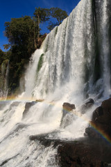 Igaucu falls with rainbow and rocks close up portrait