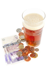 Glass of beer with banknotes and coins