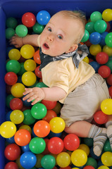 Fototapeta na wymiar Cute boy playing in a pool of plastic balls