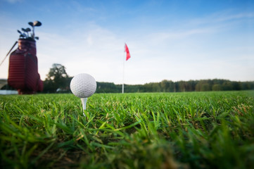 Golf ball on tee on gold course at sunset