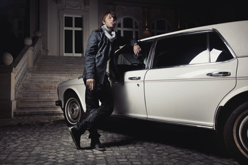Handsome young man standing next to a limousine - obrazy, fototapety, plakaty