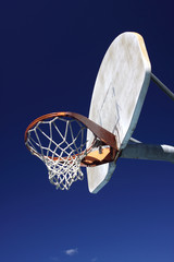 Old basketball hoop against brilliant blue sky