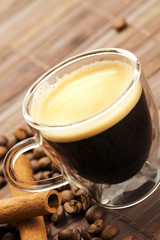 espresso in glastasse diagonal mit kaffeebohnen und zimtstangen