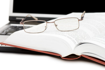 Eyeglasses and books on the laptop
