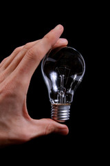 lightbulb in the hand on black baclkground © ronstik