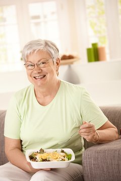 Happy senior woman eating salad