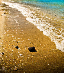 Close-up of golden beach with clear blue water washing up