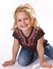 Adorable little girl on her knees smiling at the viewer