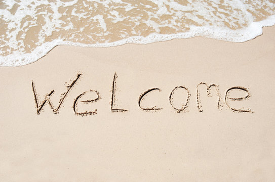 Inscription welcome on a wet sand