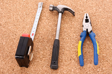 Hammer, pliers and ruller on cork board surface