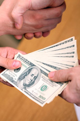 Businessman setting a deal passing money and shaking hands