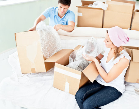 Happy Young Couple Unpacking Boxes With Glasses