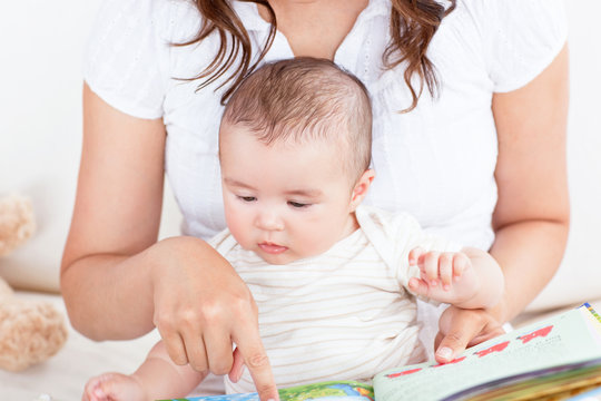 Attentive mother showing images in a book to her cute little son